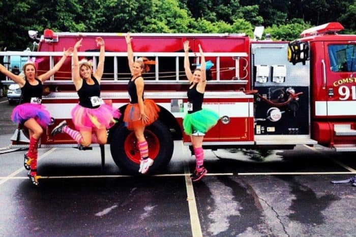 women jumping in front of a fire truck