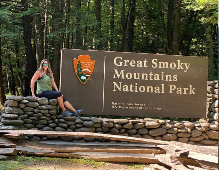 woman by sign for the Great Smoky Mountains National Park 