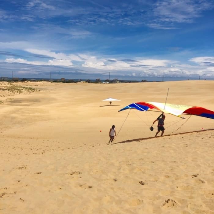 carrying a hang glider up the dune