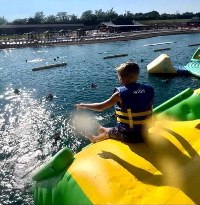 kid on top of inflatable slide on the water