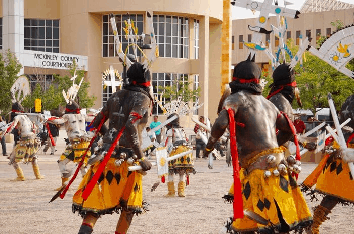 Native American dancers perform in front of a courthouse.