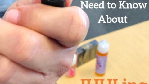 Hand holding a JUUL pod with vaping supplies and text about JUULing on a table.