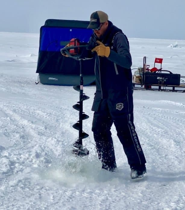 Captain JJ Malvitz drilling a hole in the ice