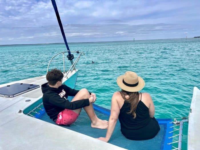 Adventure mom and son observing dolphins on sailboat