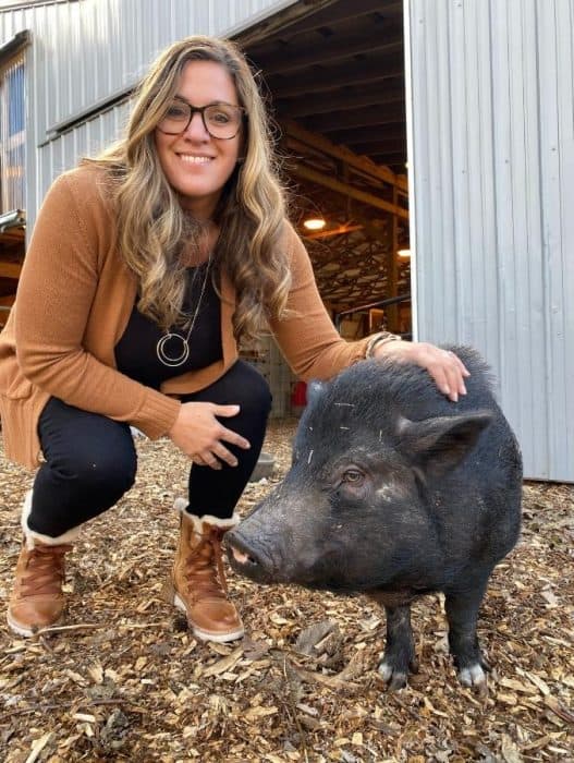 Nedra McDaniel next to a pig at Oinking Acres Farm