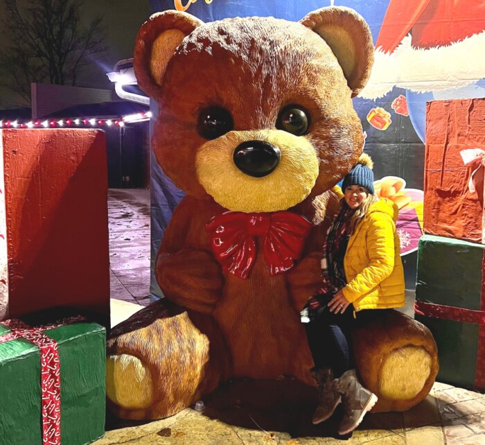 woman sitting on giant teddy bear at Land of Illusion Christmas Glow