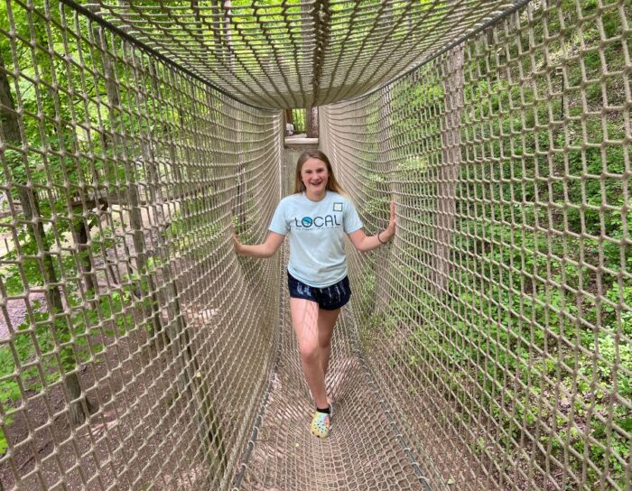 girl inside rope tunnel on Treehouse Trek at Heritage Farm 